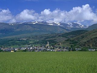 Thumbnail of Llivia from the distance with fields in the foreground and mountains in the backdrop