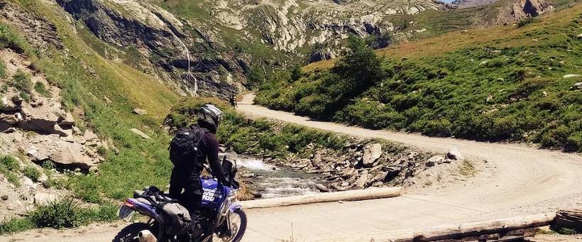 Riders traversing bridge on dust track road