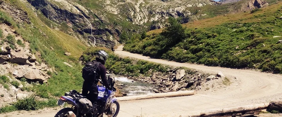 Riders traversing bridge on dust track road