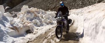 Motorcycle riding along track with deep snow on side of track